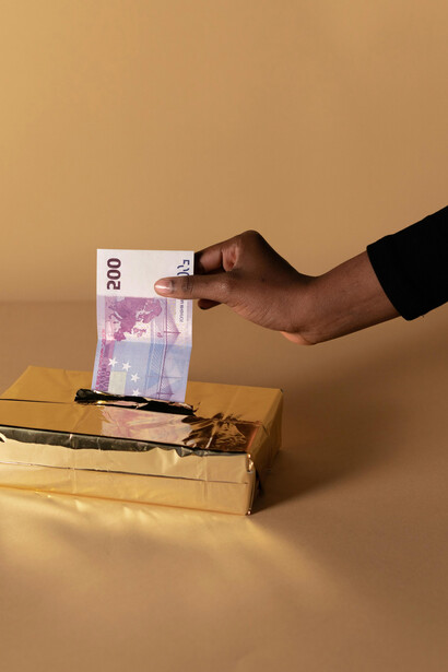 Mano de una persona poniendo dinero en una "caja de oro"
