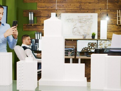 Architects examining a 3D-printed model of a real business office building, highlighting concepts such as 3D building models, virtual construction sites, and building management system interfaces