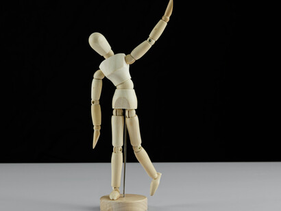 A wooden doll on a white table evokes the image of control—like invisible strings guiding human behavior