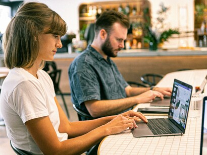 Two people with laptops sat together at a table 