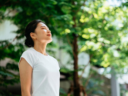 A short-haired woman in a white tank top appears upset, with her hand on her face