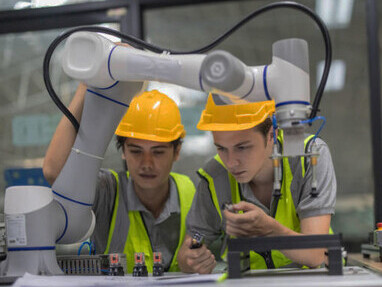 Engineers working alongside welding robot arms, showcasing the seamless integration of human expertise and AI-driven technology in industrial applications