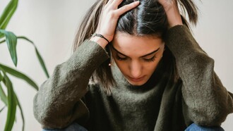 Une femme tenant sa tête dans la frustration, la douleur et la colère, probablement coincée dans une difficulté