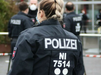 A woman in a police uniform stands in front of a building in Germany