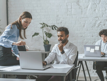 A man at a laptop inside a call center, symbolizing the hidden ghost-worker labor supporting AI technologies