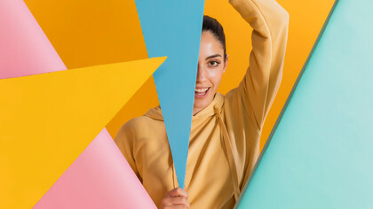 Happy woman surrounded by vibrant geometric shapes, illustrating the impact of color psychology on mood