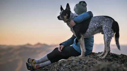 Un ragazzo e il suo amico a quattro zampe si godono il tramonto da un'altura
