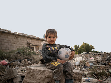 A boy seated with a football in Baghdad, Baghdad Governorate, Iraq
