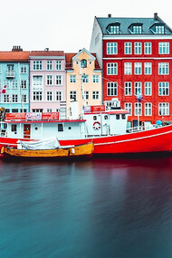 A charming scene unfolds in Copenhagen, Denmark, where a boat rests gently alongside a dock, exuding serene winter vibes