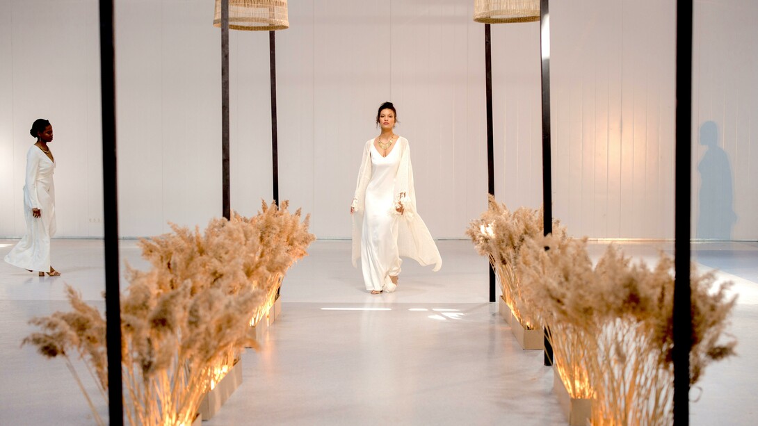 Uma modelo usando um vestido branco andando na passarela