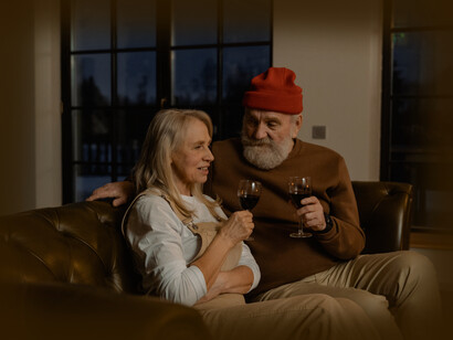 An older couple sitting together and enjoying a glass of red wine
