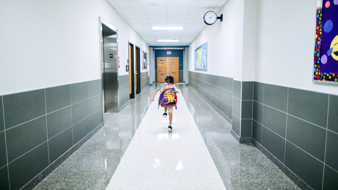 Criança percorrendo o corredor em direção a sala de aula de sua escola
