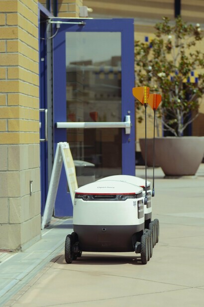 A delivery robot next to a building 