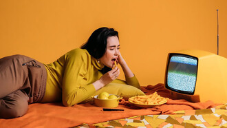 Woman lying on orange floor looking at television