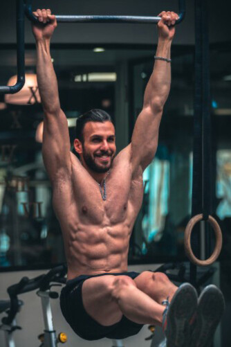 A muscular man lifting weights, portrayed as a fitness influencer, highlights the pressure to achieve six-pack abs and the growing issue of male body dysmorphia