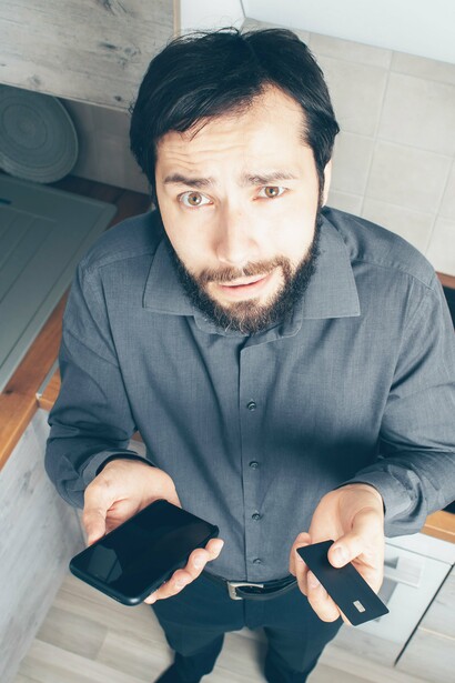 Man looking confused holding phone and credit card