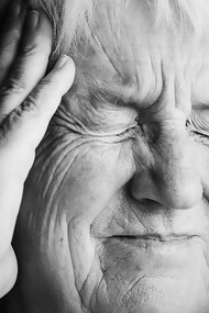 Elderly woman experiencing a stroke, holding her head in pain