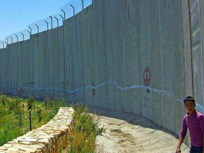 Un ragazzo palestinese si trova accanto alla barriera di separazione israeliana a Betlemme, 2009