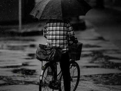 A cyclist shielding themselves with an umbrella from all the rain in the Netherlands
