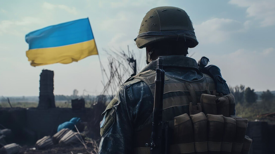In the warzone, a Ukrainian soldier stands resolute, wearing a helmet and standing behind, vigilant and determined as he surveys the surroundings