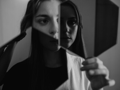 A woman holds mirrors that reflect her own image