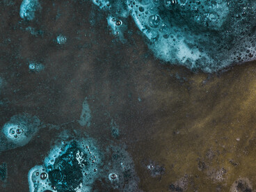 Murky, blue-green liquid with scattered bubbles evokes the hidden toxicity and complexity of polluted water systems