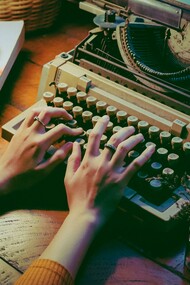 A lady busy writing on her typewriter