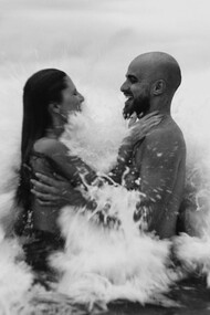 Amidst the serene embrace of ocean waves, this couple embodies the volatile beauty of passion, where impulsive decisions and memories collide in a dance of love and conflict