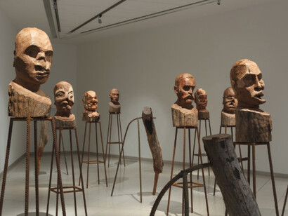 Kader Attia, Yo acuso, 2016. Instalación, bustos de madera sobre base de metal