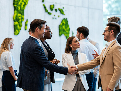 Diplomats and corporate representatives engaging in discussions and handshakes at a global networking event