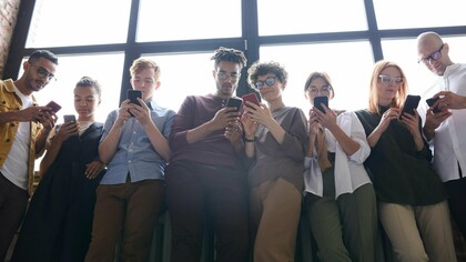 Un groupe de jeunes adultes fait défiler leurs téléphones, inconscients de leur environnement