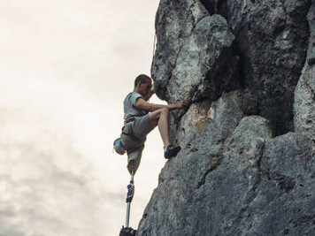 Rock climbing with a prosthetic leg, a disabled man pushes his limits, embodying courage and perseverance