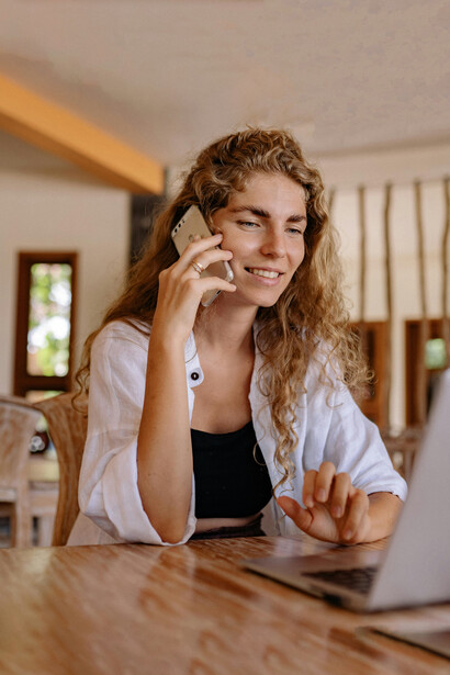Secretaria hablando por teléfono mientras está en la computadora. Los asistentes virtuales más famosos en computadoras y móviles emplean voces femeninas