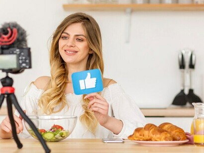 A woman, serving as a food influencer, showcases her home cooking in a video, illustrating the impact of social media on culinary trends