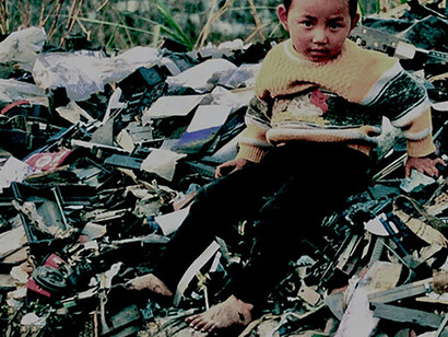 Boy in Guiyu, China, atop a pile of electronic waste