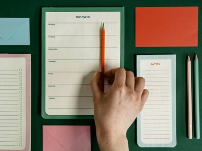 A neatly arranged planning desk with a person holding a pencil, symbolising clarity found through organisation