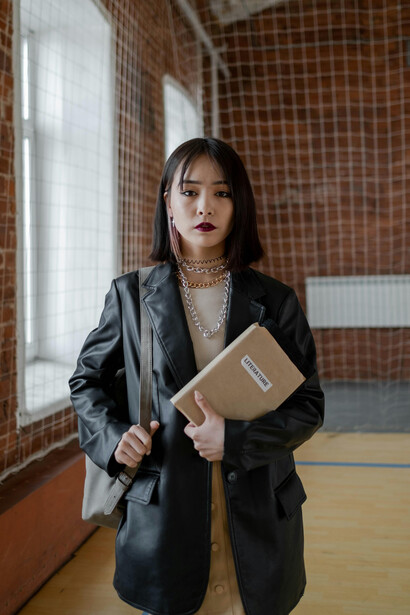 Woman in a black leather jacket holding a brown paper bag, facing bullying at school