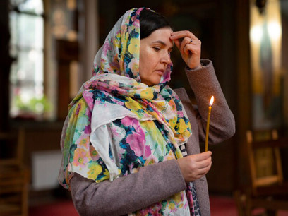 A woman in church, holding a candle while praying, seeking inner strength and divine guidance