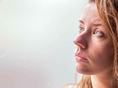Donna che guarda con espressione assorta e malinconica fuori da una finestra