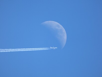 Avión en cielo azul con luna al fondo