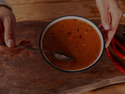 A woman savors a bowl of tarhana soup presented on a charming wooden tray
