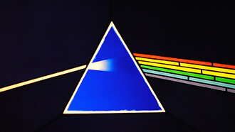 "Discover a captivating close-up of a stained glass reproduction showcasing part of the iconic cover artwork for Pink Floyd's 'The Dark Side of the Moon', exhibited at the renowned Pink Floyd: Their Mortal Remains exhibition hosted at the Victoria and Albert Museum