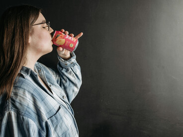 A woman drinking soda from a can in the kitchen