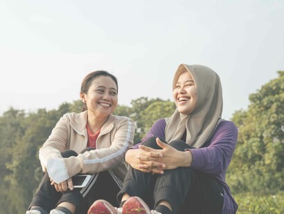 Two friends, one enjoying through laughter and the other reacting with a wide smile