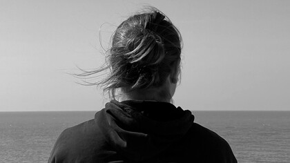 A woman looks at the horizon by the sea