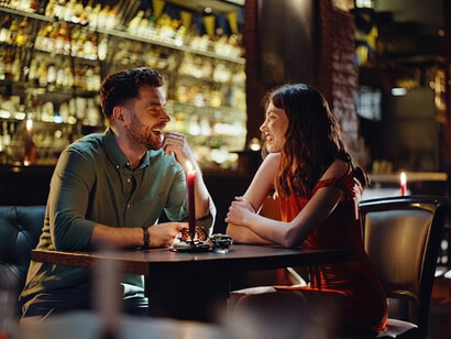 A cheerful couple enjoys each other’s company during a relaxed date in a stylish, softly lit bar