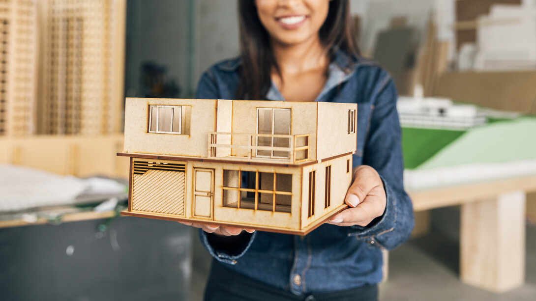 Smiling African American woman holding a model of a portable house