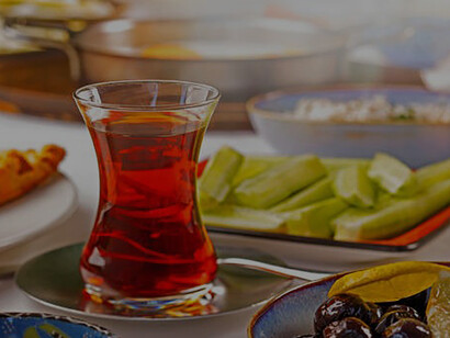 Amidst the setting, a tableau emerges -a quintessential Turkish-style breakfast. Plates adorned with an array of culinary delights and cups brimming with aromatic tea take center stage on the table
