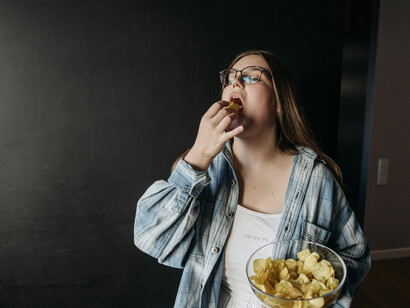 A woman holding a bowl of chips, representing a low-effort, imperfect meal aesthetic