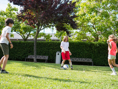 Young children playing football on a grassy field